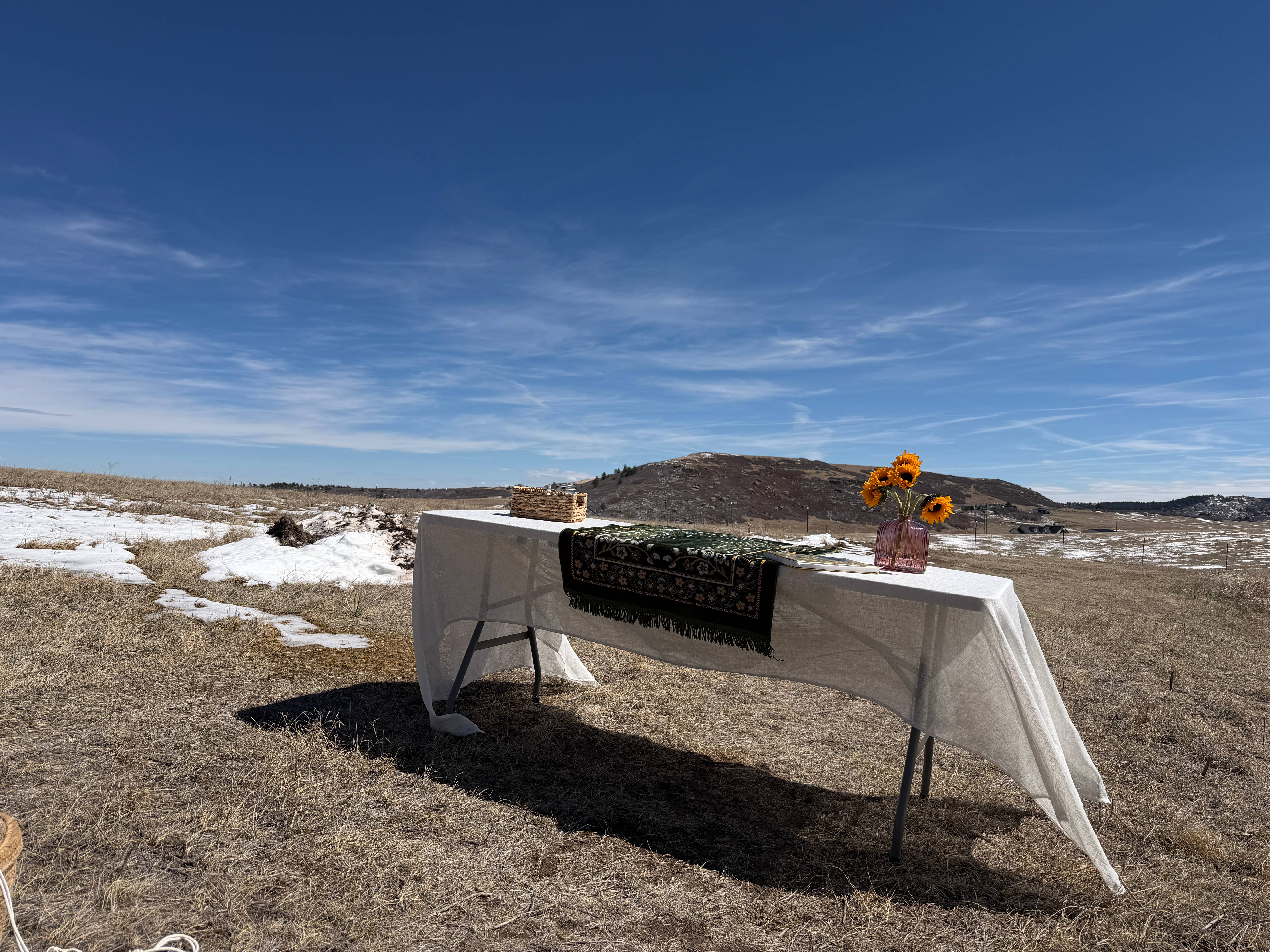 Ceremony setup with table, decorative runner, and sunflowers in Colorado landscape